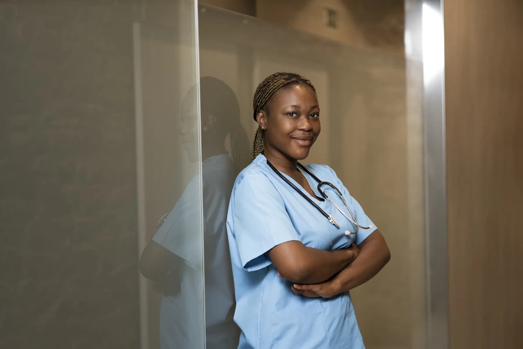 A nurse in scrubs smiling in a clinic corridor